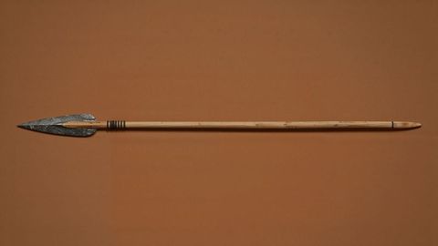 Caveman spear with stone tip on brown background