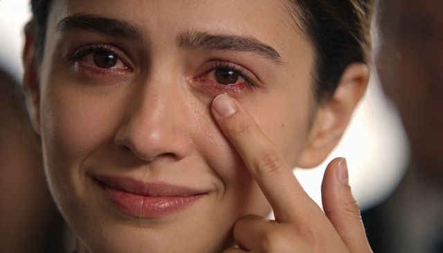 Close-up emotional portrait woman touching tear at event, intimate melancholic expression
