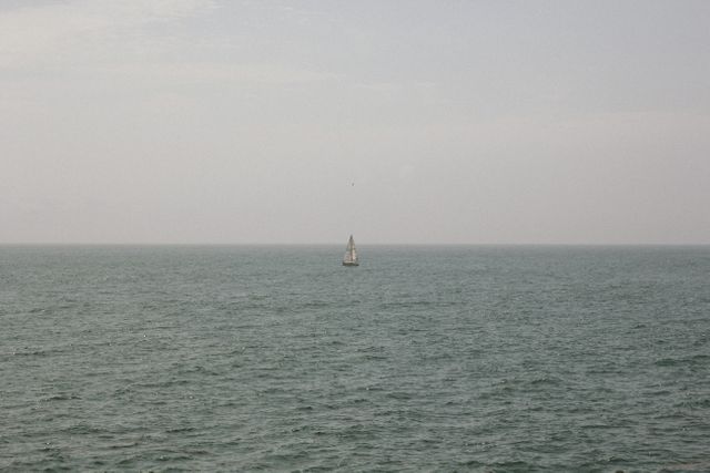 Solitary Boat Sailing on Calm Sea Under Cloudy Sky - Download Free Stock Images Pikwizard.com