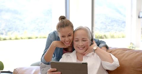 Smiling Grandmother and Granddaughter Using Tablet at Home