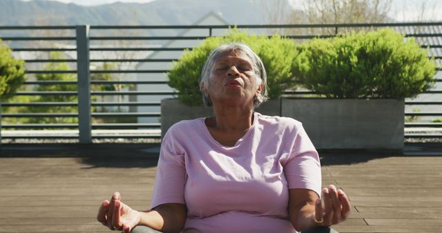 Image of relaxing senior african american women meditating in the garden. Retirement lifestyle, active leisure time.