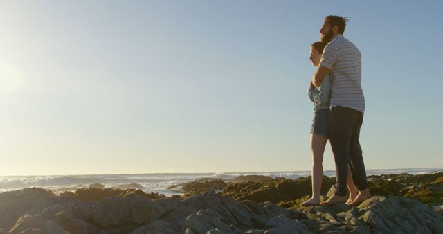 Romantic young couple embracing on rock at beach. Couple looking at sea 4k