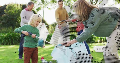 Family cleaning together in garden — child using litter picker with light blue trash bag