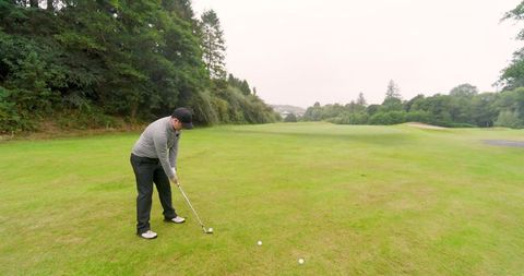 Male Golfer Prepares Swing on Lush Golf Course