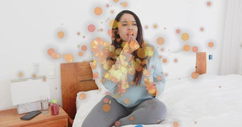 Indian woman holding pill jar and taking single pill while sitting cross-legged on bed