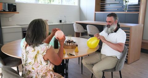 Senior couple preparing celebration at home with balloons