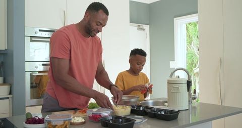 African american father and son preparing healthy meals together in modern kitchen