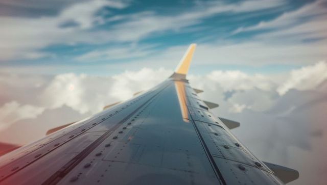 Airplane Wing Above Clouds Scenic View from Passenger Seat