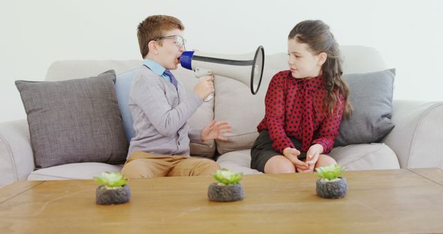 Boy Shouting Through Megaphone at Girl Sitting on Sofa - Download Free Stock Images Pikwizard.com