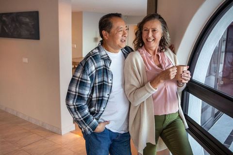 Senior Couple Relaxing by Arched Window with Coffee Mug at Home