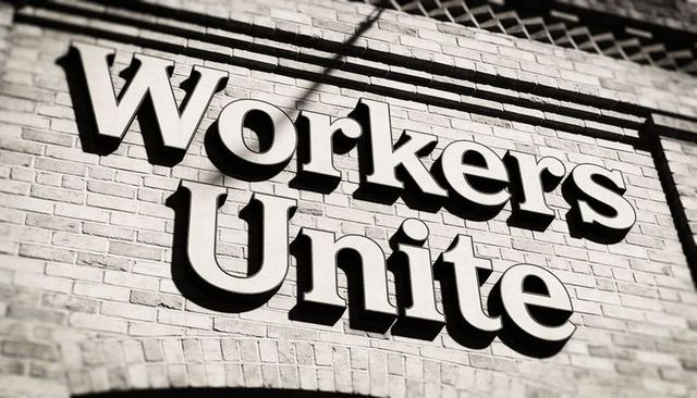 Workers unite 3d sign casting deep shadows on brick facade with metal grille