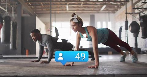 Partners holding planks in gym training with boxing bags and social media counter