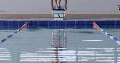 Swimmers Preparing for Dive on Starting Block at Poolside