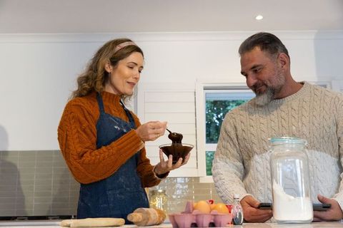 Couple baking together in cozy kitchen stirring chocolate and preparing dough