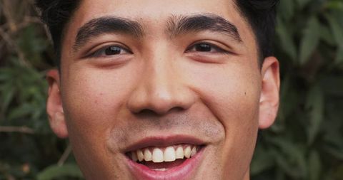 Smiling asian man closeup portrait outdoors showing natural joy and friendly expression