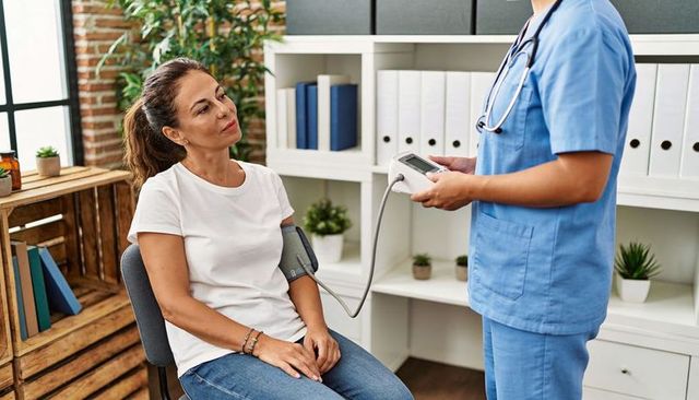 Nurse measuring blood pressure for relaxed woman in modern clinic with natural light