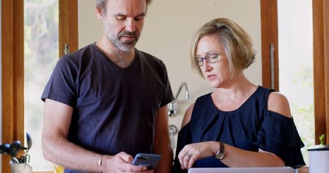 Couple Navigating Smartphone Technology in Home Kitchen