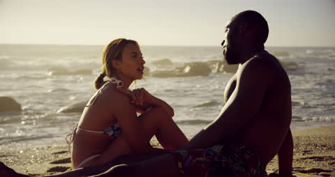 Interracial Couple Relaxing on Beach During Sunny Day
