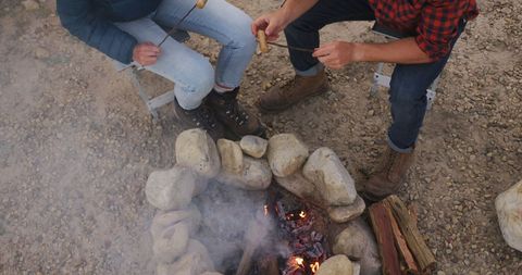 Couple Toasting by Campfire Amidst Tranquil Mountain Scenery