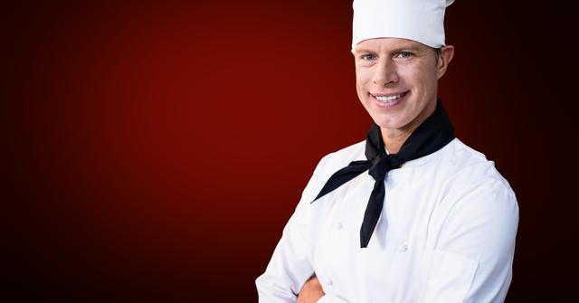Chef smiling confidently with arms crossed, wearing white chef uniform and hat. Ideal for culinary magazines, restaurant advertisements, and promotional materials related to cooking and hospitality industry.