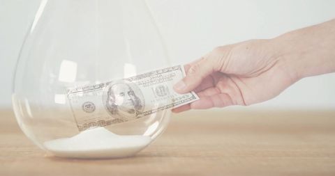 Hand Balancing Dollar Bill Over Hourglass with Sand - Download Free Stock Images Pikwizard.com