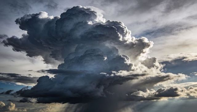 Rising Cumulonimbus Thundercloud Tower with Anvil, Turrets and Rain Shafts, Crepuscular Rays