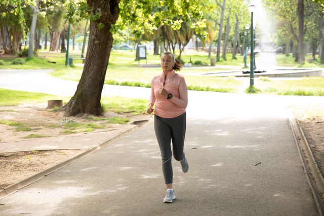 Senior Caucasian woman working out in the park wearing sports clothes, running. Retirement healthy lifestyle activity.