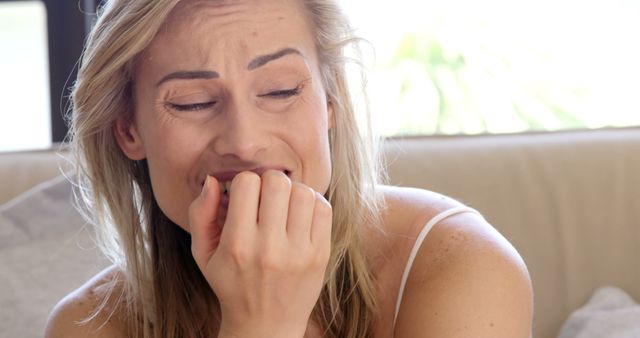 Seated women crying while eating her nail in her bed