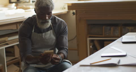 Elderly Carpenter in Workshop Checking Smartphone with Focus