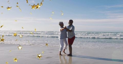 Senior Couple Dancing on Beach with Golden Star Confetti