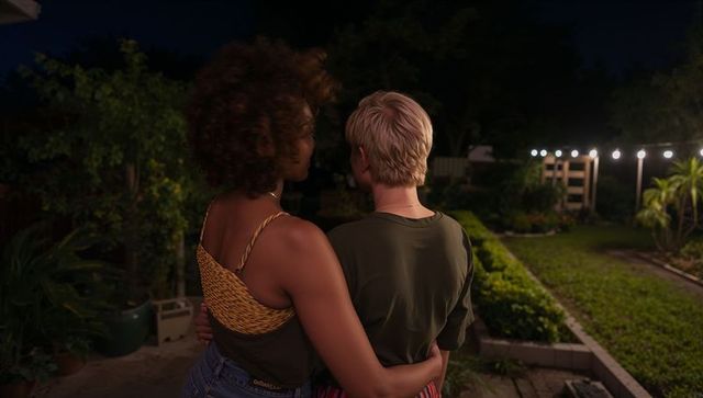 Intimate couple embracing on backyard patio under warm string lights at night
