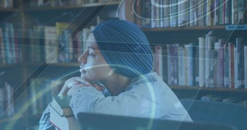 Young woman wearing navy headwrap leaning on books in cozy library with soft light overlay
