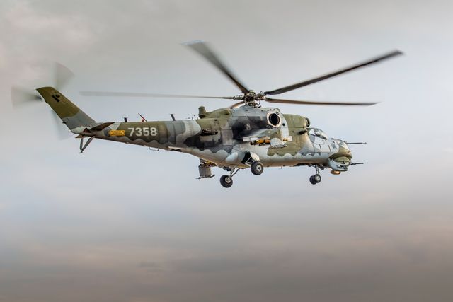 This stock photo features a camouflage-patterned military helicopter in mid-flight against a neutral sky backdrop. Ideal for use in articles related to aviation technology, military defense strategies, aircraft engineering, and transportation. The dynamic perspective can enhance content on armed forces' air mobility, combat readiness, and advanced rotorcraft design.
