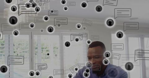 African american man working remotely focusing on laptop with messaging bubbles overlay