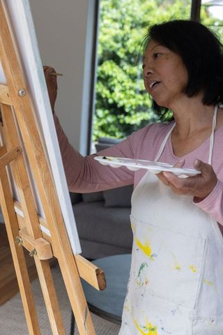 Woman Painting on Canvas in Living Room with Sunlight