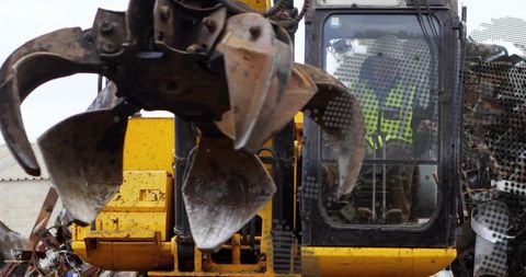 Excavator with claw grapple handling metal in scrap yard
