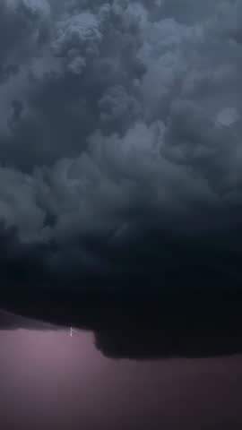 Vertical storm video showing towering thunderclouds charging with lightning over plain
