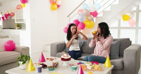 Two Women Celebrating Cozily at Home Birthday Party with Snacks
