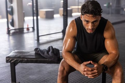 Sweaty Male Athlete Resting on Bench After Intense Gym Workout Showing Determination