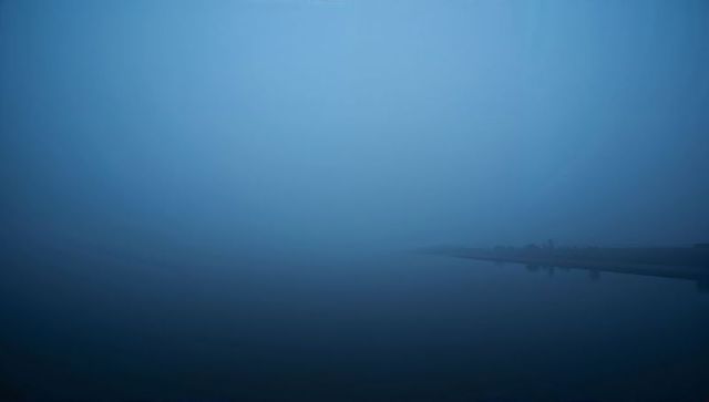 Blue foggy lake dawn minimalist waterfront reflection evoking quiet calm and solitude