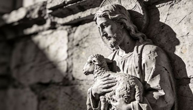 Bearded saint holding lamb stone sculpture on church facade with weathered texture
