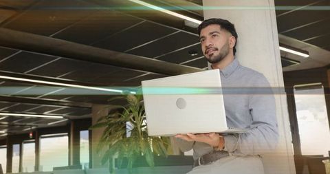 Professional man holding laptop in modern office space