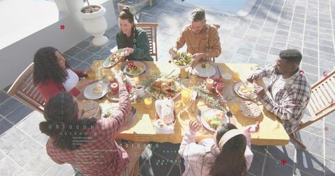 Group sharing rooftop brunch around sunlit wooden table passing plates and enjoying meal