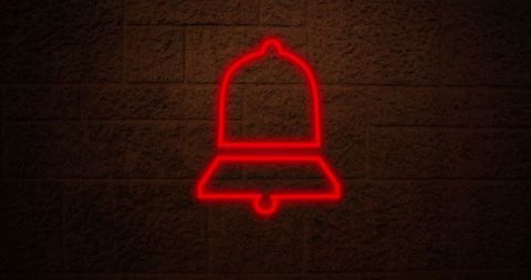 Glowing red neon bell sign against brick wall at night
