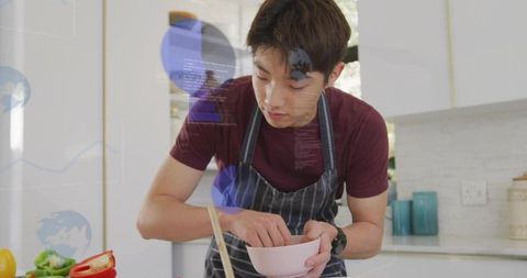 Korean teen cooking in modern kitchen mixing fresh vegetables in pink bowl for meal prep