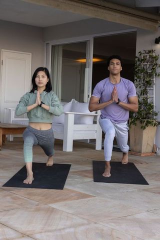 Diverse Couple Practicing Yoga Poses Outdoors on Patio