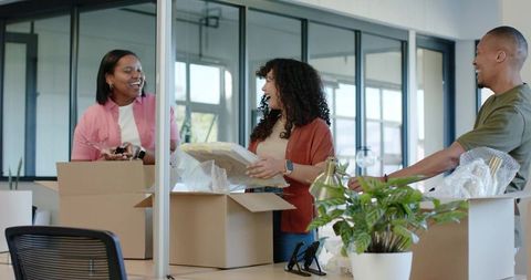 African american coworkers unpacking office boxes during team move and workspace setup