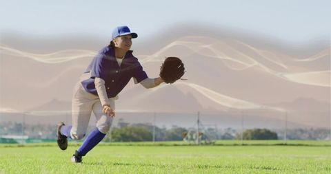 Female Outfielder Lunging to Catch Ball in Blue Baseball Uniform on Sunlit Grass Field