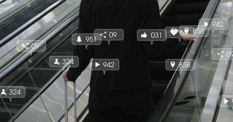 Business traveler checking smartphone on airport escalator with suitcase and social icons
