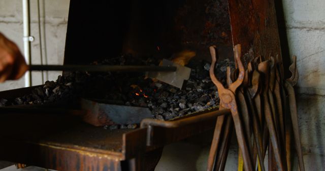 A blacksmith's tools are arranged next to a forge with hot coals, indicating a traditional metalworking process. Focus on the craftsmanship and the age-old techniques that are still used by artisans today.